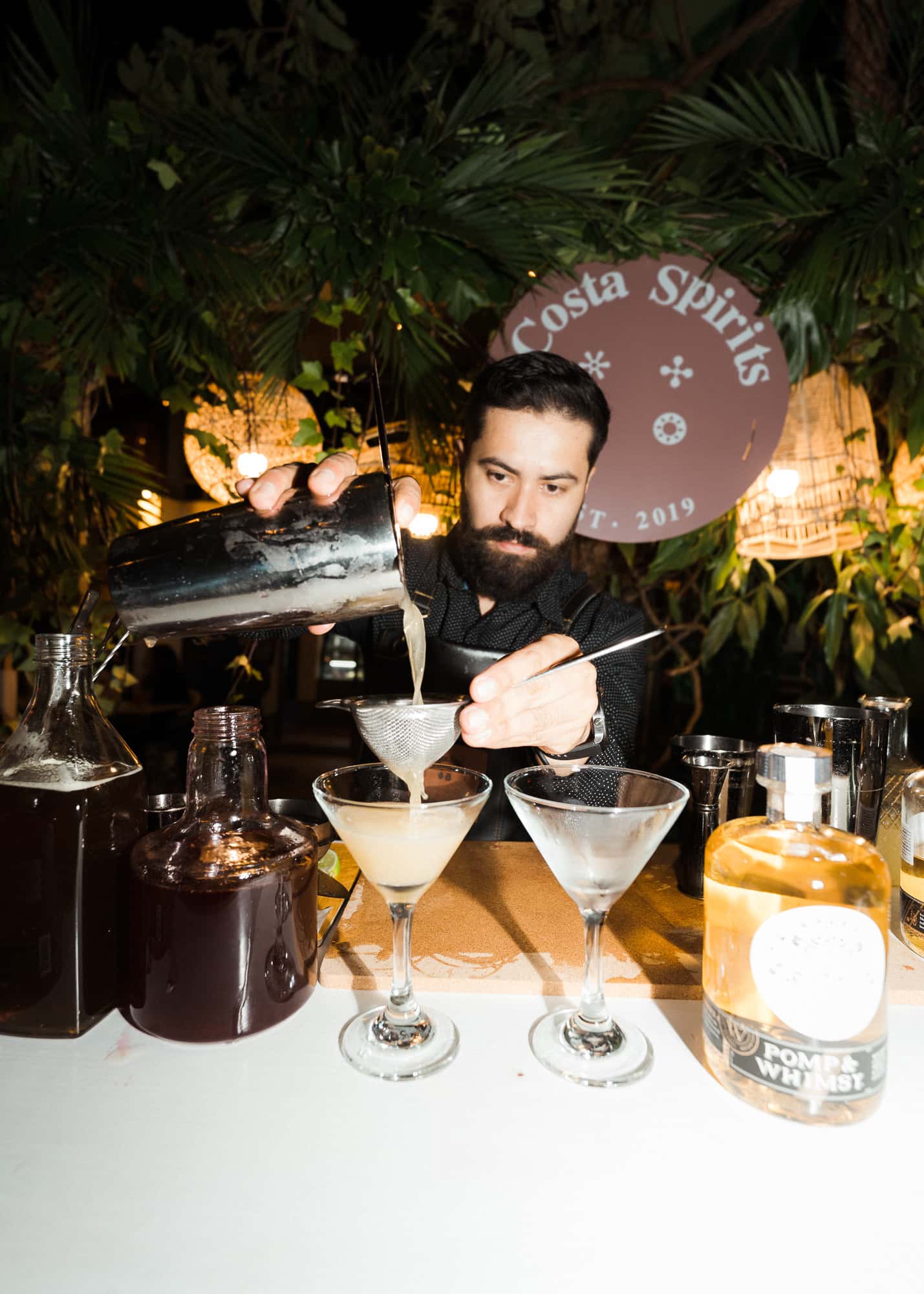 A bartender pouring two coupes at a Costa Spirits event